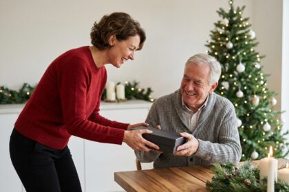 Femme souriante offrant un coffret cadeau à un homme âgé